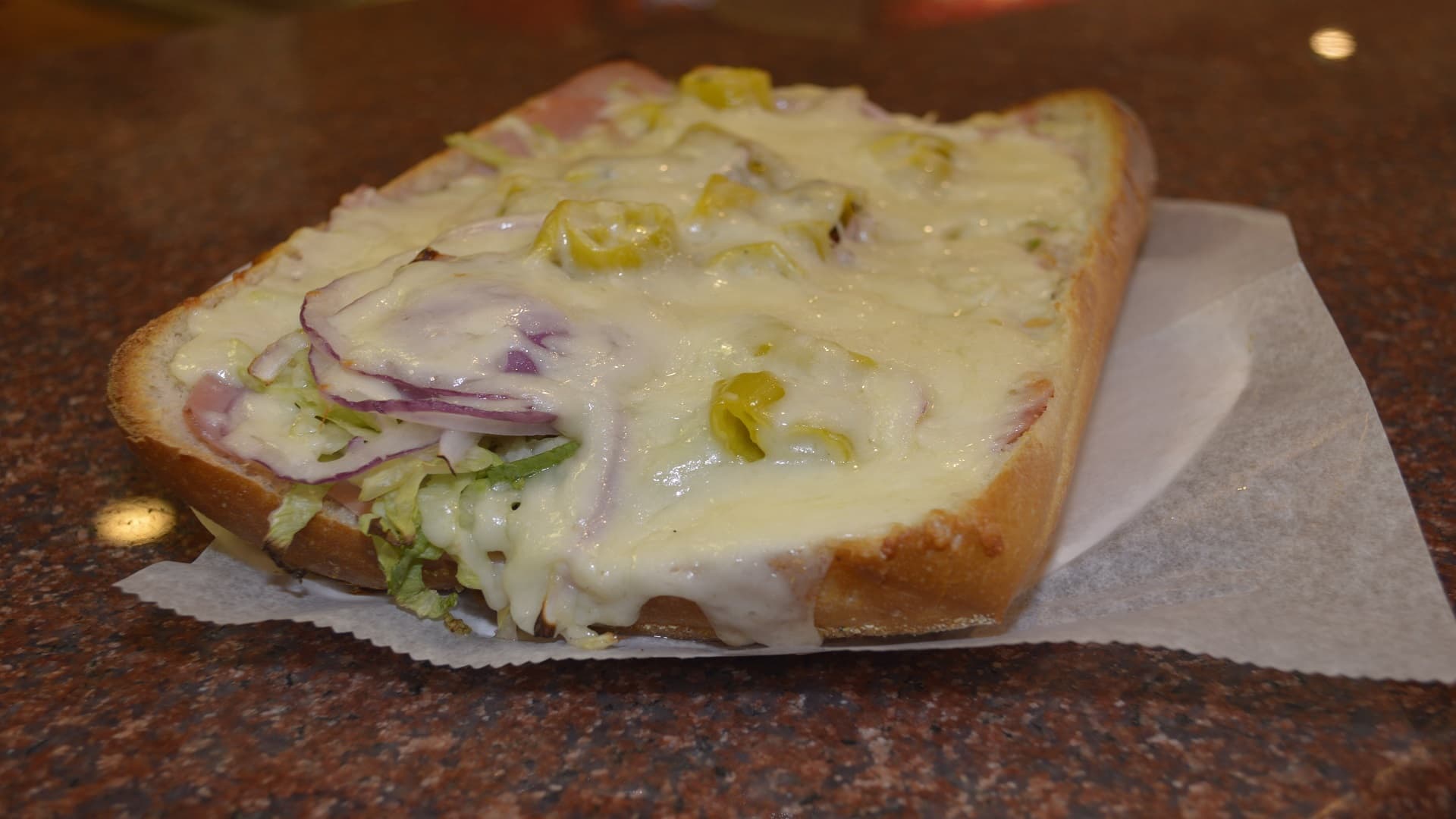 Delicious Italian hero with spicy peppers smothered with mozzarella cheese